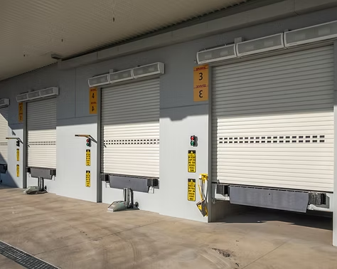 A spacious warehouse featuring multiple large roll-up doors for loading and unloading goods