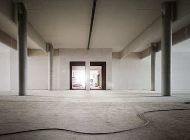 An Empty Room Featuring Concrete Floors And Exposed Pillars