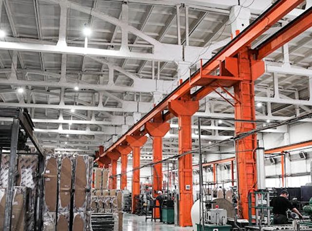 A Factory Interior Featuring Orange Steel Beams And Numerous Stacked Boxes Throughout The Space
