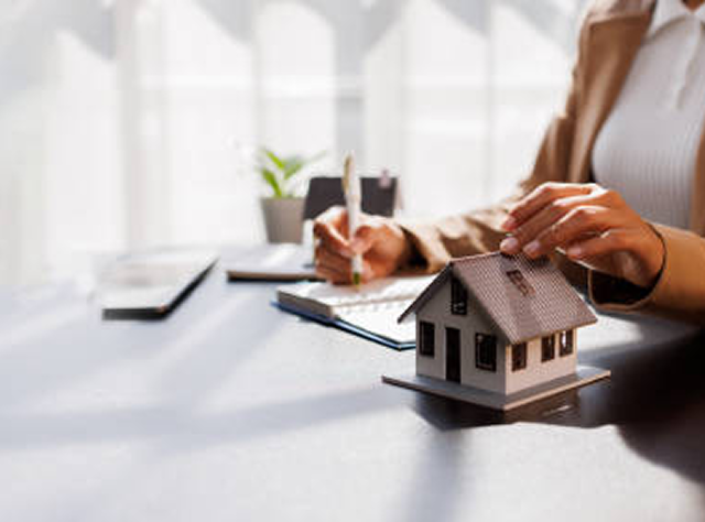 A Woman At A Desk Studies A House Model