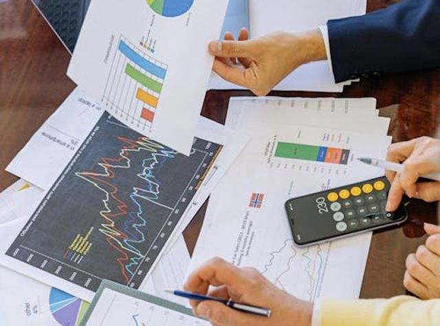 Team Of Business People Engaged In Paperwork And Utilizing A Calculator For Data Analysis And Financial Tasks