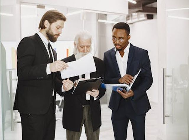 Three Business Men In An Office Reviewing Documents Together